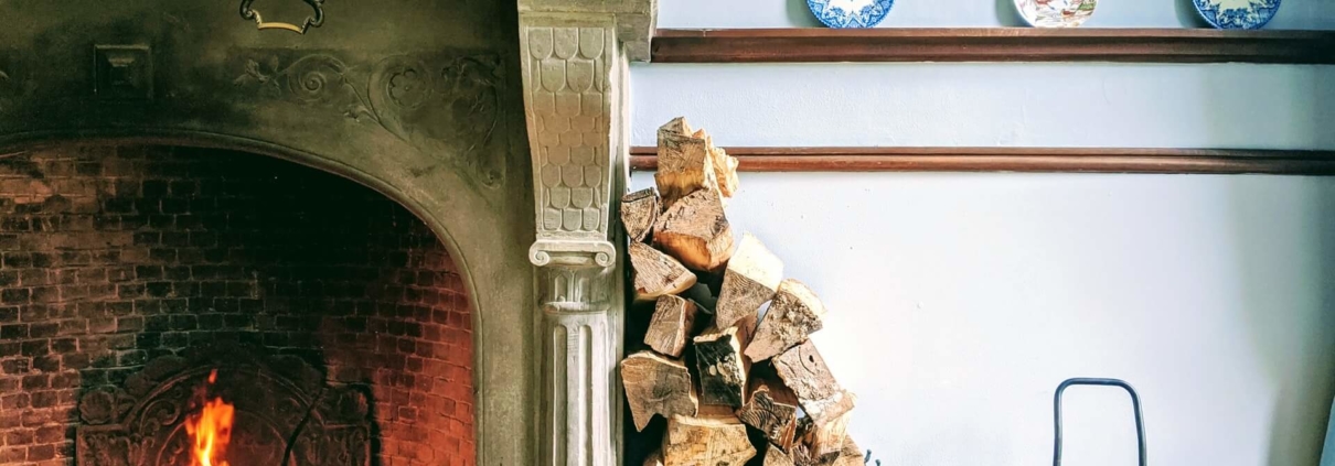Firewood stacked against a wall in a home that is properly preserving the life of their fireplace that is also burning well