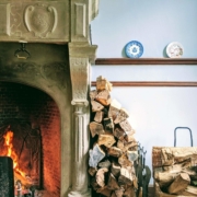 Firewood stacked against a wall in a home that is properly preserving the life of their fireplace that is also burning well