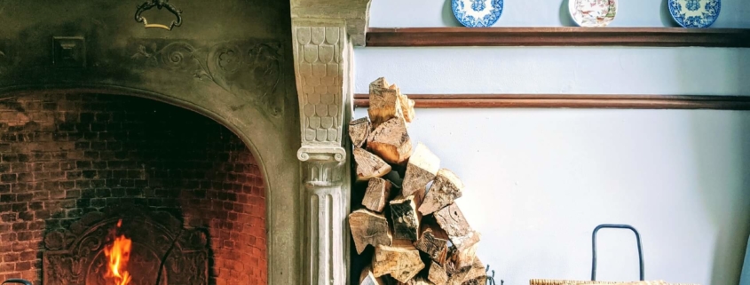 Firewood stacked against a wall in a home that is properly preserving the life of their fireplace that is also burning well