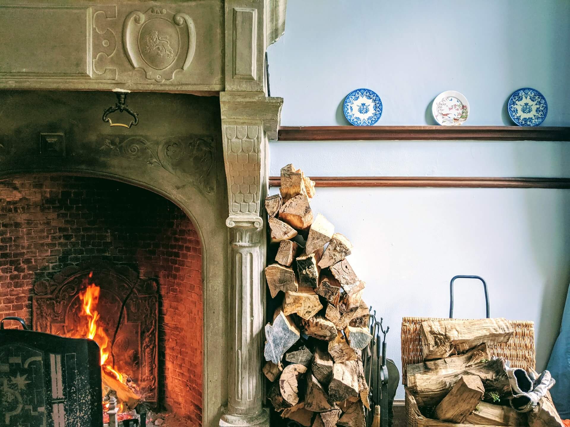 Firewood stacked against a wall in a home that is properly preserving the life of their fireplace that is also burning well