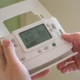 A person holding their thermostat control examining it for any HVAC myths.