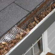 A dirty, clogged gutter causing home problems as a result of not cleaning gutters regularly.