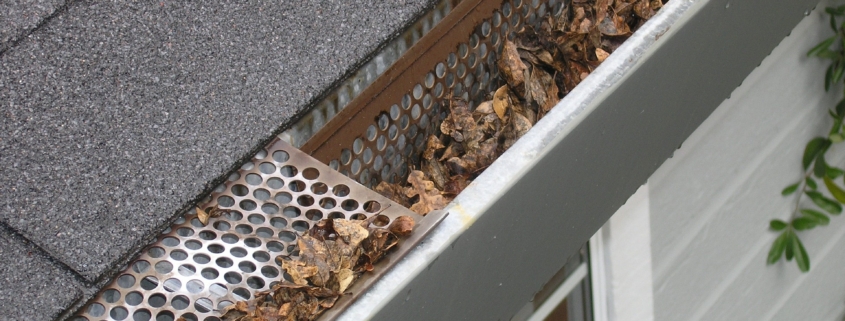 A dirty, clogged gutter causing home problems as a result of not cleaning gutters regularly.