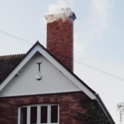 A smoking chimney on top of a residential house in northern virginia that would need chimney cleaning in different seasons.