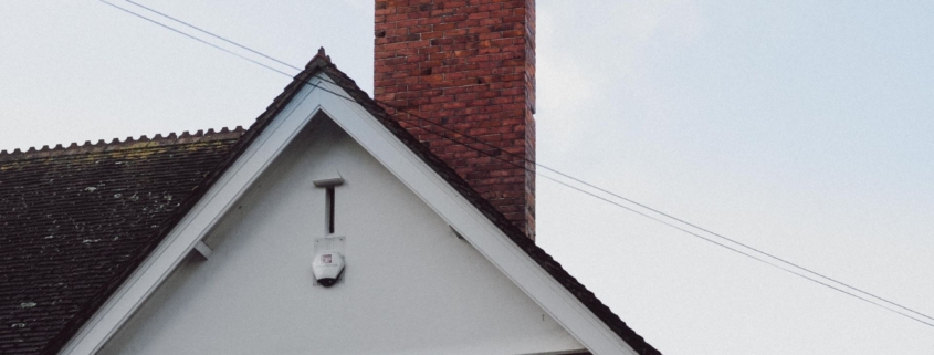 A smoking chimney on top of a residential house in northern virginia that would need chimney cleaning in different seasons.