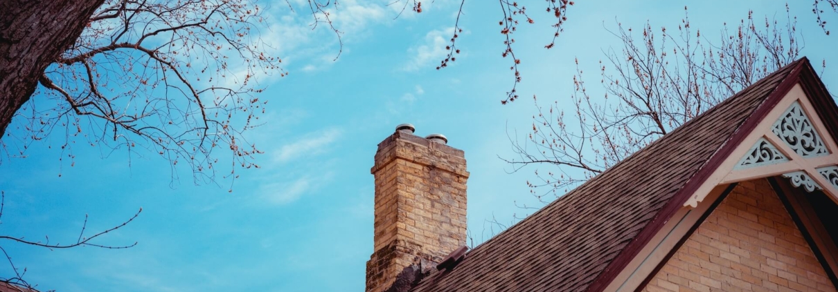 A Chimney with ciimney damage on top of a house