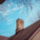 A Chimney with ciimney damage on top of a house