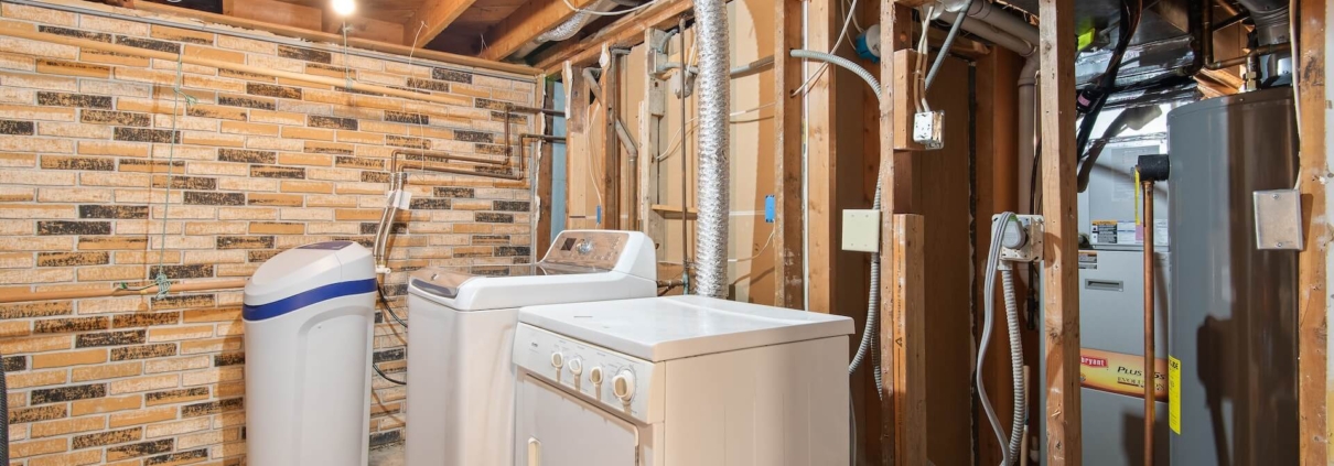 White washer and dryer in unfinished basement laundry room