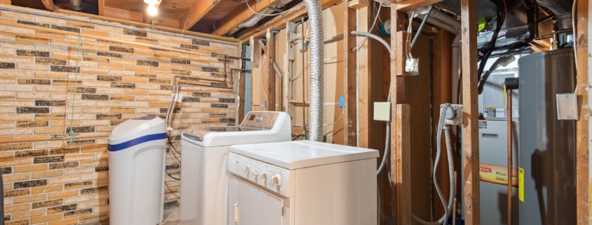 White washer and dryer in unfinished basement laundry room